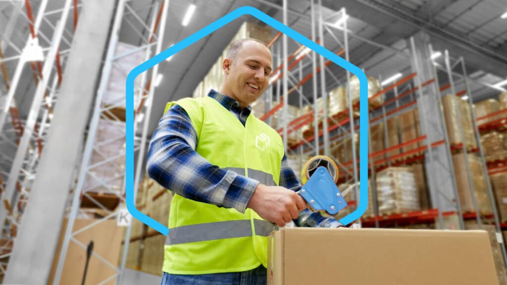 Man in bright green vest taping a box in a warehouse Order Fulfillment